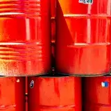 Bright red industrial oil barrels stacked outdoors in daylight, showcasing vivid color and industrial theme.