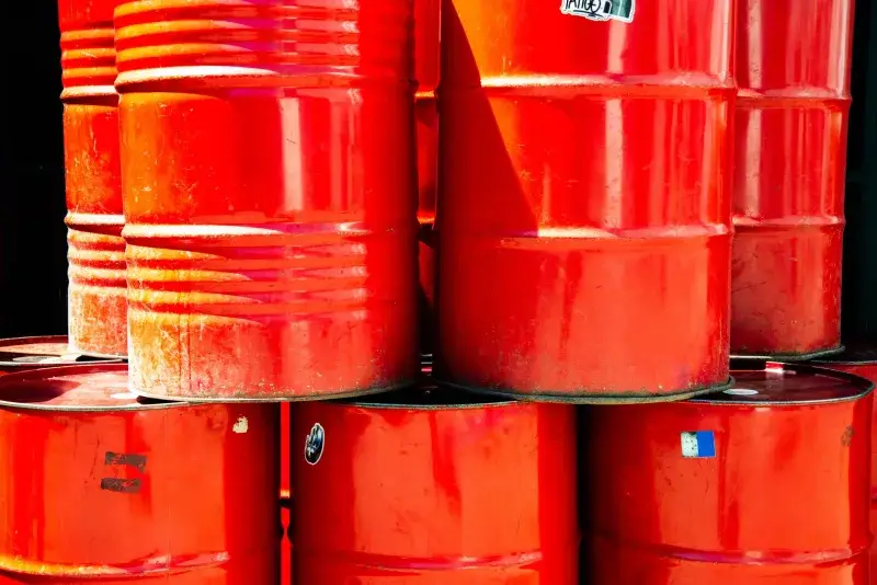 Bright red industrial oil barrels stacked outdoors in daylight, showcasing vivid color and industrial theme.