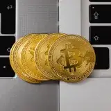 Close-up of Bitcoin coins resting on two laptop keyboards, representing digital currency and technology.