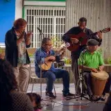 Un grupo diverso de músicos mayores actuando al aire libre en Venezuela, mostrando talento musical tradicional.