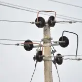 High-resolution image of a utility pole with insulators and power lines against a clear sky