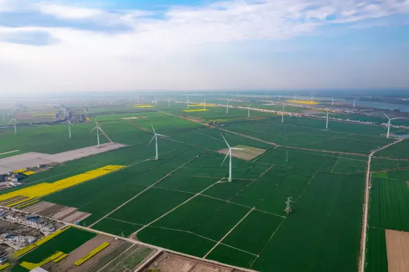Expansive aerial view of wind turbines across farmland in Jiujiang, China, highlighting sustainable energy.