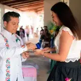 A couple exchanges rings during a vibrant wedding ceremony indoors, surrounded by guests.