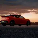 Luxury car parked at sunset with city skyline, highlighting modern design and vibrant colors.