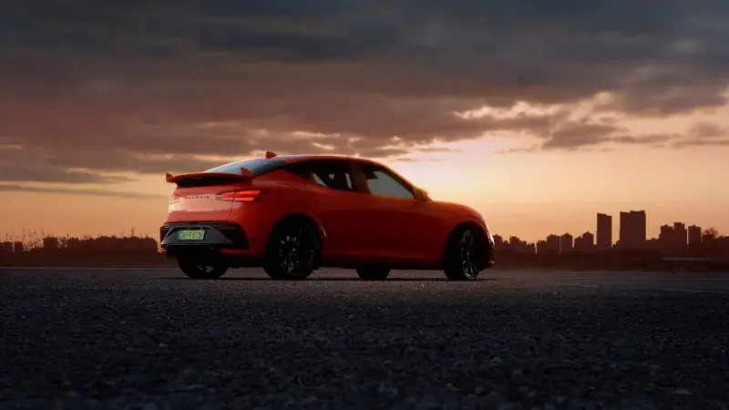 Luxury car parked at sunset with city skyline, highlighting modern design and vibrant colors.
