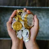 Close-up of hands holding gold and silver cryptocurrency coins, symbolizing digital investment.