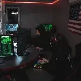 Hackers in a dim room working on cyber security systems with multiple screens and digital data.
