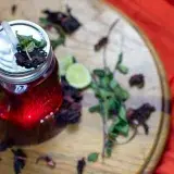 Overhead view of Agua de Jamaica with lime and mint on a wooden surface.