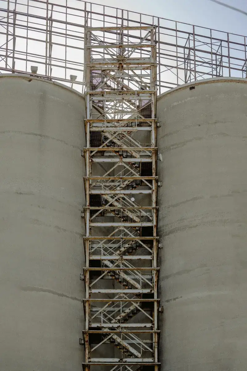 Close-up of industrial silos featuring a vertical staircase in an urban setting.