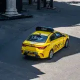 A yellow Uber taxi driving on a city street, shown from above.