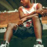 Young athlete in Chicago Bulls jersey sitting outdoors in contemplation.