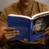 Close-up of a person reading 'Poder Sem Limites' by Tony Robbins indoors.