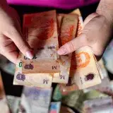 Hands holding Argentine peso notes, representing currency and finance in Buenos Aires, Argentina.
