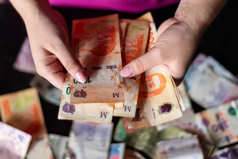 Hands holding Argentine peso notes, representing currency and finance in Buenos Aires, Argentina.