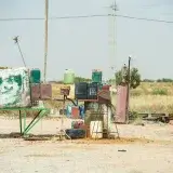 Rustic scene of an abandoned gas station with barrels in the Tunisian desert, showcasing neglect.