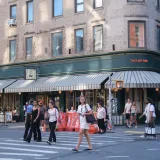 People crossing the street near Jack's Wife Freda cafe on a sunny day.