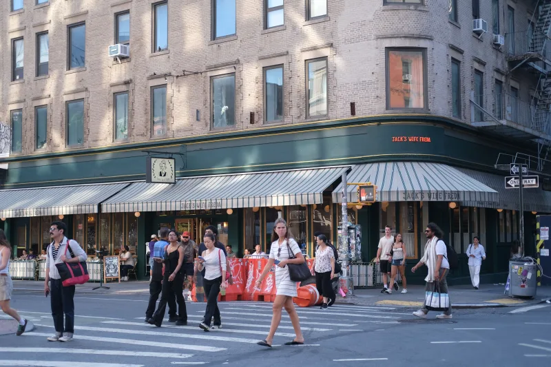 People crossing the street near Jack's Wife Freda cafe on a sunny day.