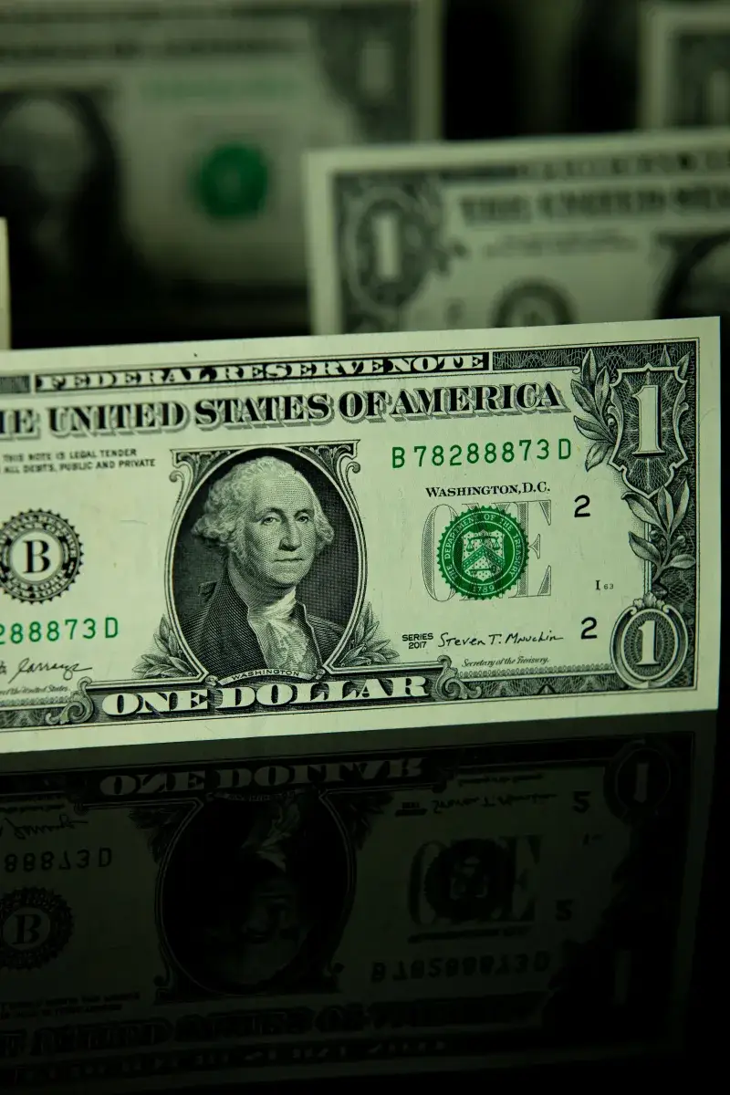 Detailed shot of a US dollar bill on a reflective surface, highlighting currency design.