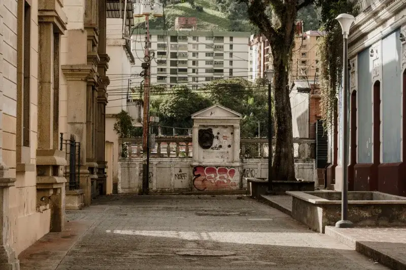 Quiet urban alley in Mérida, Venezuela, with historic architecture and lush greenery.
