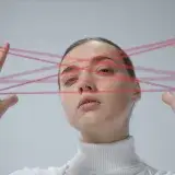 Creative portrait of a woman interacting with a red string art concept.