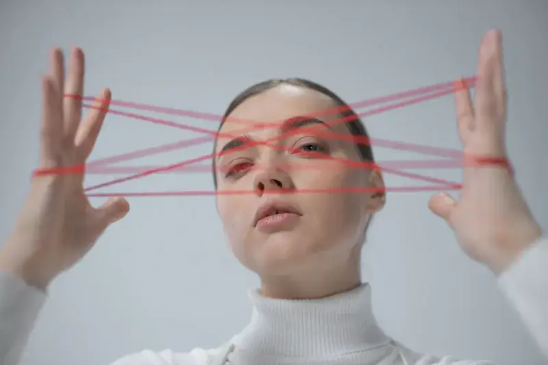 Creative portrait of a woman interacting with a red string art concept.