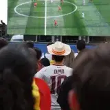 Crowd of football fans viewing a game on a large screen outdoors in Madrid.