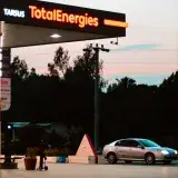 A car at a TotalEnergies station in Tarsus, Türkiye during sunset.