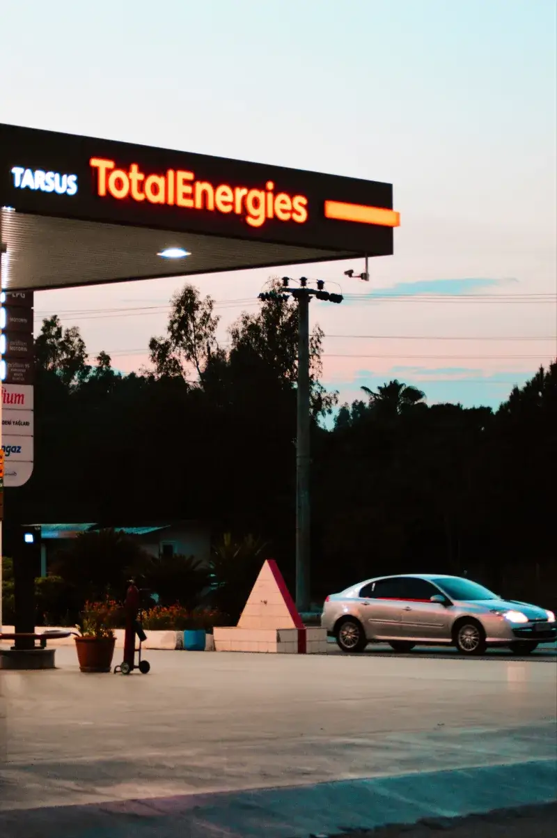 A car at a TotalEnergies station in Tarsus, Türkiye during sunset.