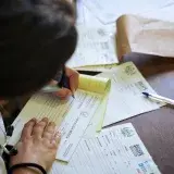 A doctor fills out medical forms indoors, focusing on patient care and documentation.