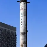 Vertical view of SpaceX rocket displayed in Dubai against clear blue sky.