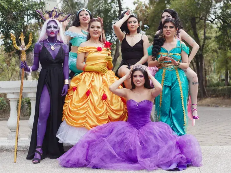 A group of women in Disney character costumes posing outdoors, embodying iconic princesses.