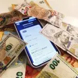 A smartphone displaying a currency converter surrounded by dollar and euro banknotes, highlighting exchange rates.