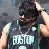 Retrato de un hombre a la moda con ropa deportiva de Boston Celtics, gafas de sol y collar, exudando estilo fresco.