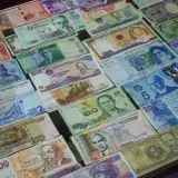 From above collection of various colorful banknotes from different countries arranged in row on table