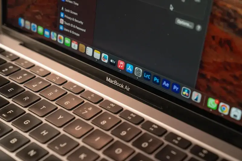 Vista detallada de un MacBook Air con enfoque en el teclado y la pantalla que muestra iconos de aplicaciones.