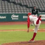 A baseball pitcher throws a pitch in a rainy stadium during a game.