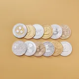 A collection of digital cryptocurrency coins, including Bitcoin and Ethereum, arranged on a stylish gold backdrop.