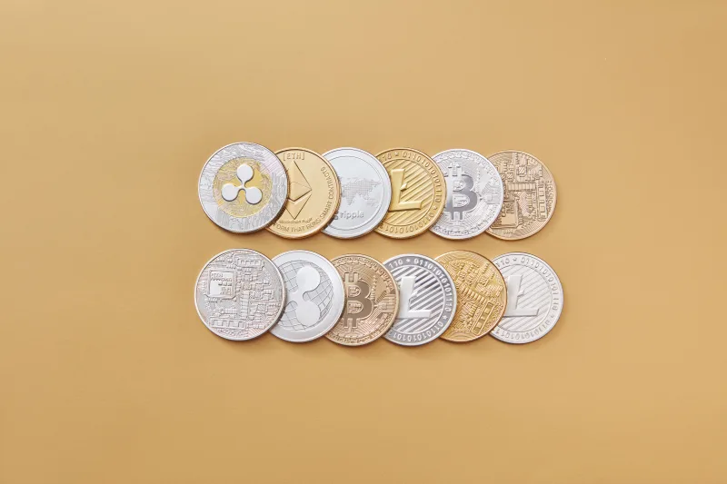A collection of digital cryptocurrency coins, including Bitcoin and Ethereum, arranged on a stylish gold backdrop.