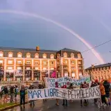 People protesting against oil exploration in Mar del Plata, Argentina under a striking double rainbow.