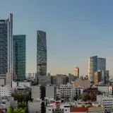 Panoramic view of Mexico City's skyline featuring Torre BBVA and Torre Reforma during sunset.
