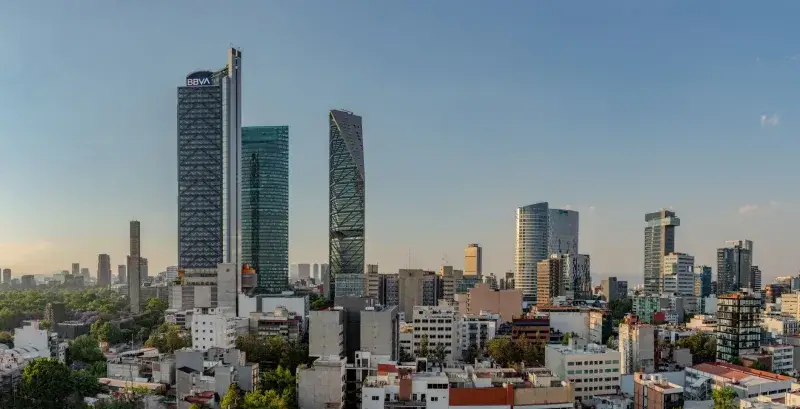 Panoramic view of Mexico City's skyline featuring Torre BBVA and Torre Reforma during sunset.