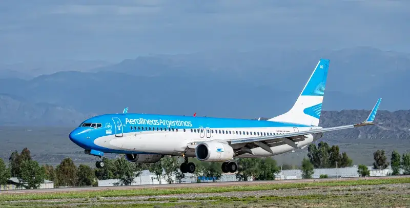 Avión de Aerolíneas Argentinas aterrizando frente a un fondo montañoso en Argentina.