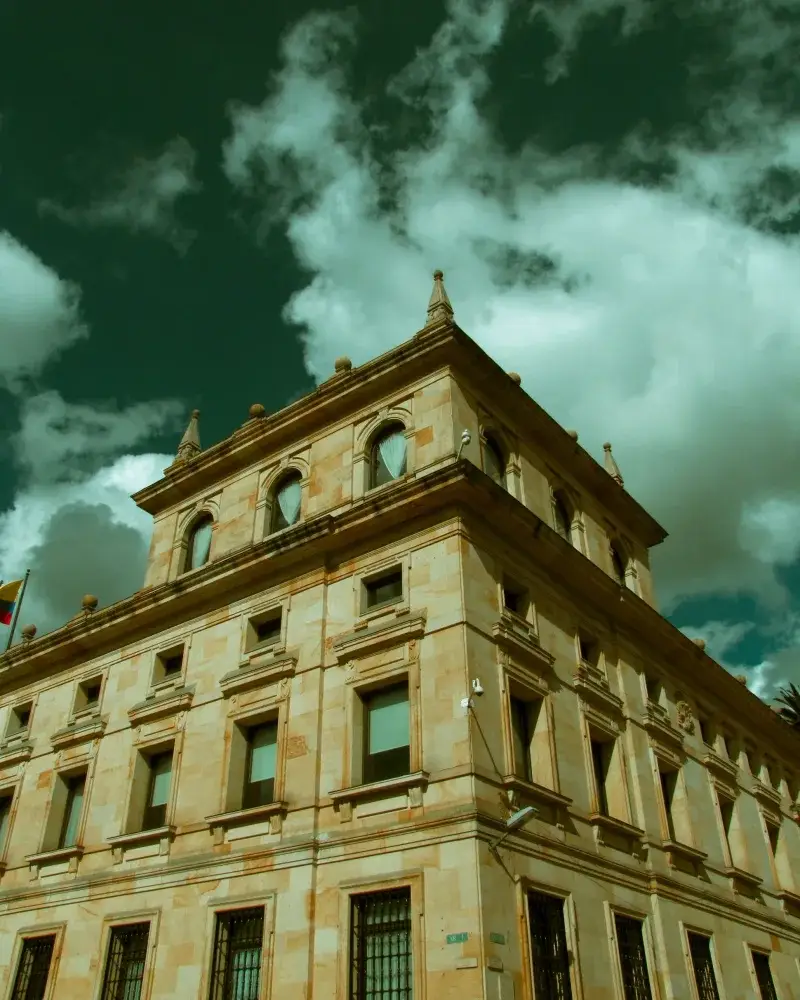 Low angle shot of a historic stone building against a cloudy sky in Bogotá, Colombia.