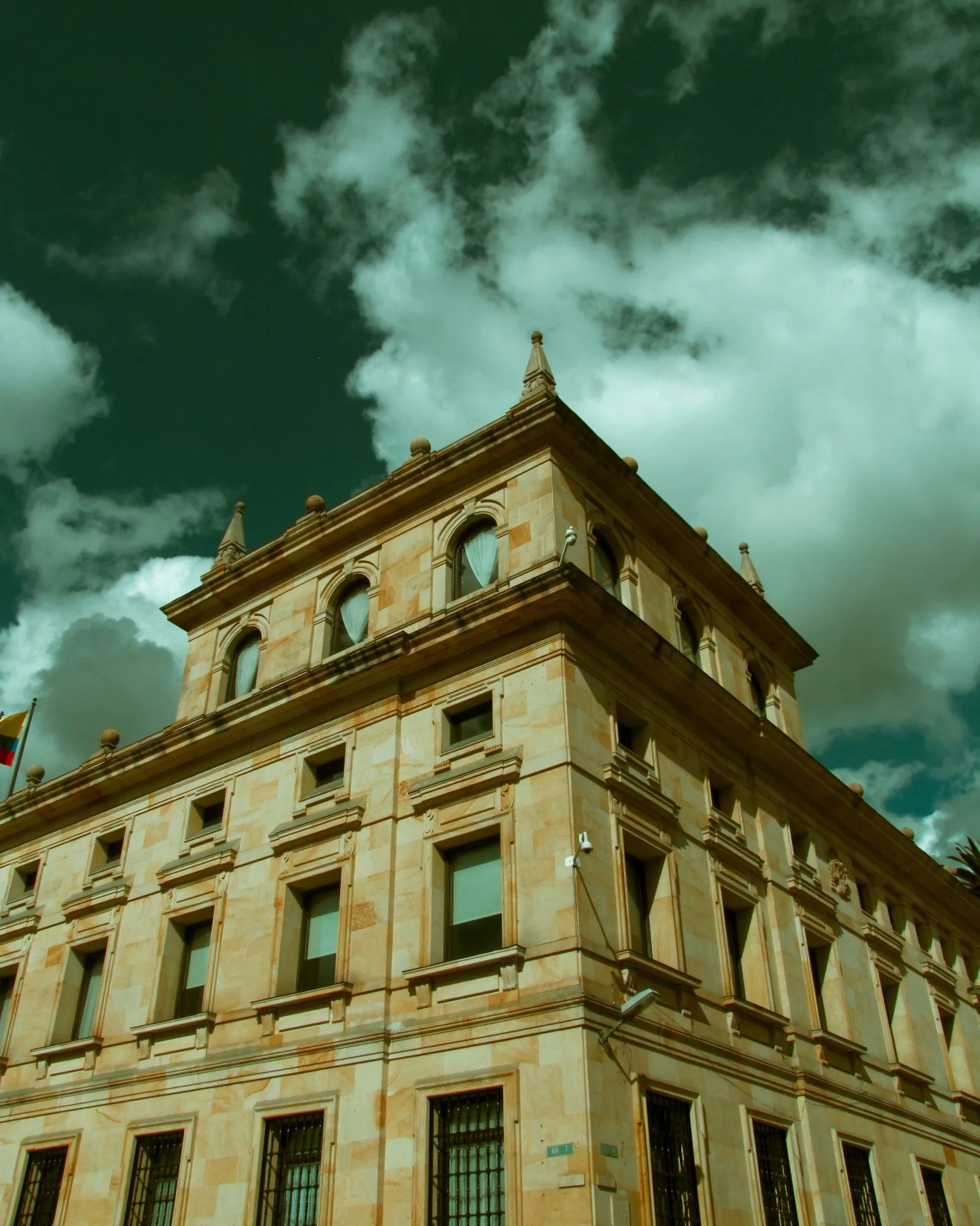 Low angle shot of a historic stone building against a cloudy sky in Bogotá, Colombia.