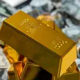Close-up of shiny gold bars stacked on a pile of cash, representing wealth and investment.