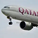 A close-up view of a Qatar Airways airplane's landing gear during flight against the sky.
