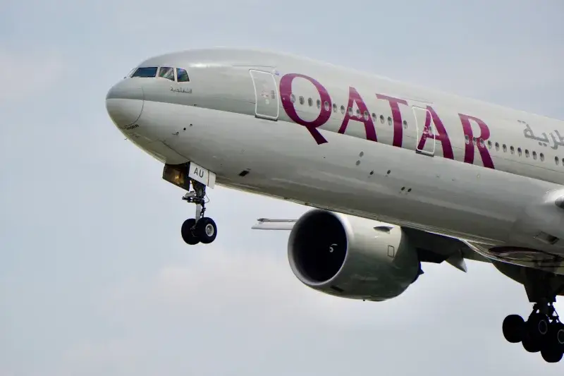 A close-up view of a Qatar Airways airplane's landing gear during flight against the sky.