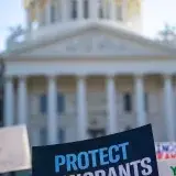 Sign reading 'Protect Immigrants' seen at a protest in front of the California State Capitol in Sacramento.