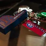Detailed shot of Texas Rangers memorabilia keychains on a glass surface, capturing sports enthusiasm.