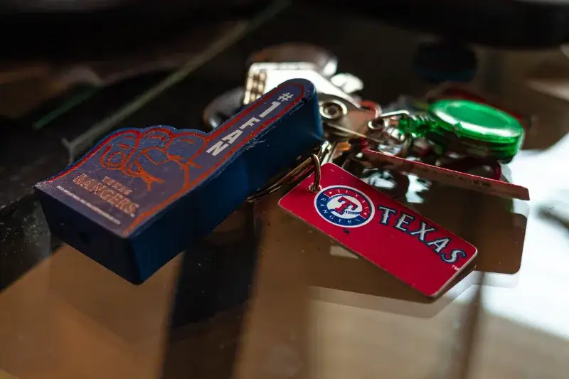 Detailed shot of Texas Rangers memorabilia keychains on a glass surface, capturing sports enthusiasm.